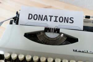 Typewriter with paper sticking out saying donations 